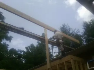 Carpenter setting a ridge beam over a new addition frame — Ice Dam Removal by Roofing Brothers in Rochester Mills