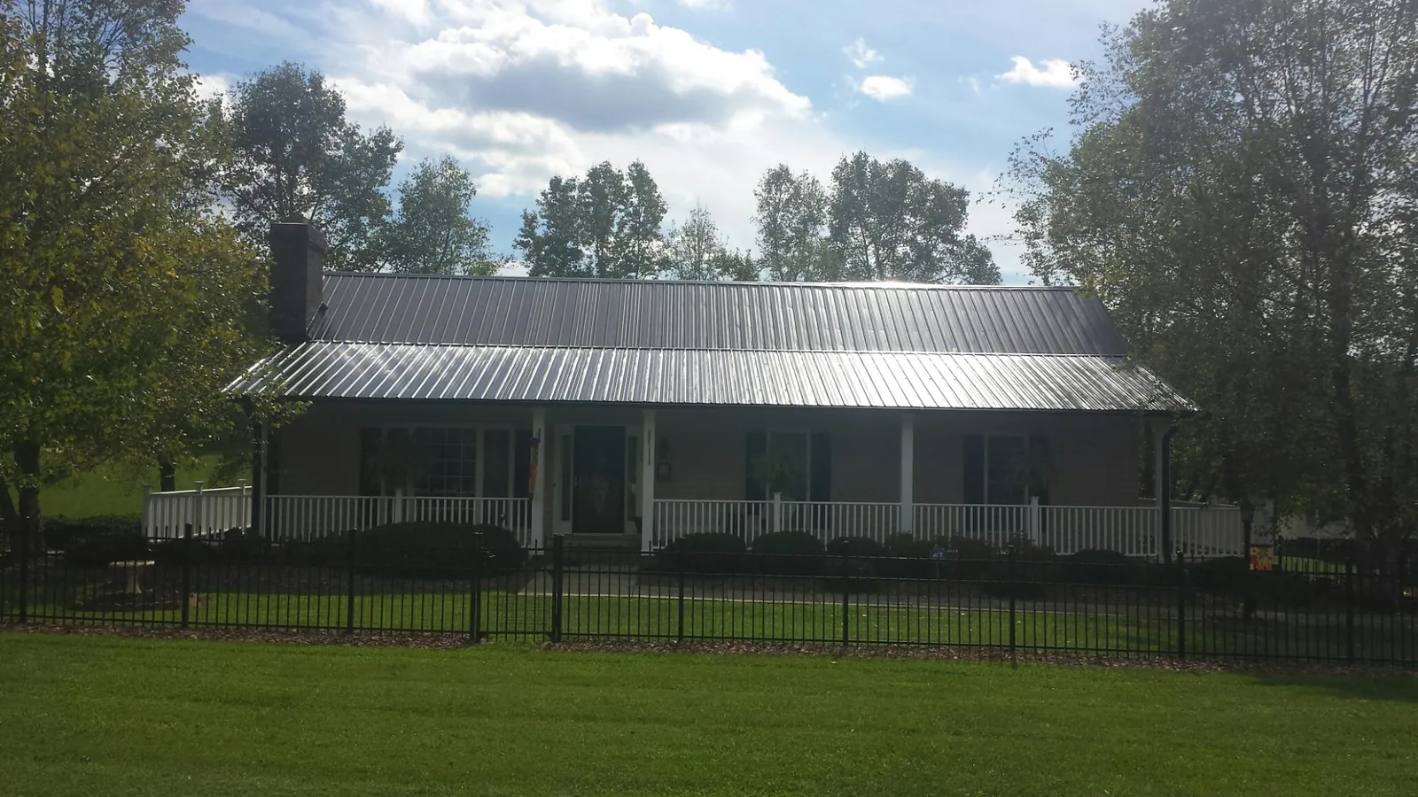Gray metal roof on a brick ranch with a full width front porch — Gutter Guard Installation work by our crew in Rochester Mills