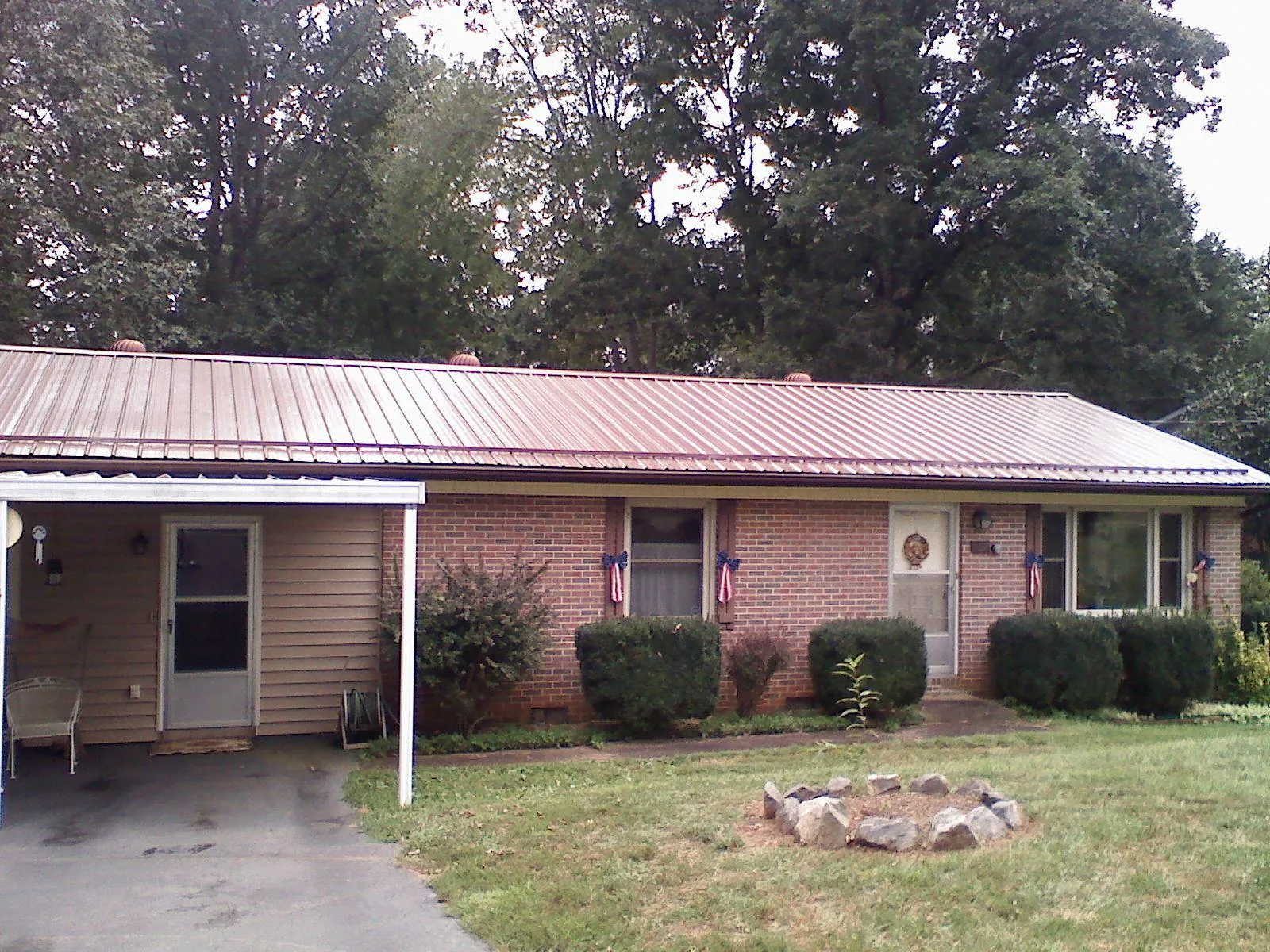 Bronze metal roof and carport on a brick ranch home — Roof Repair work by our crew in Rochester Mills