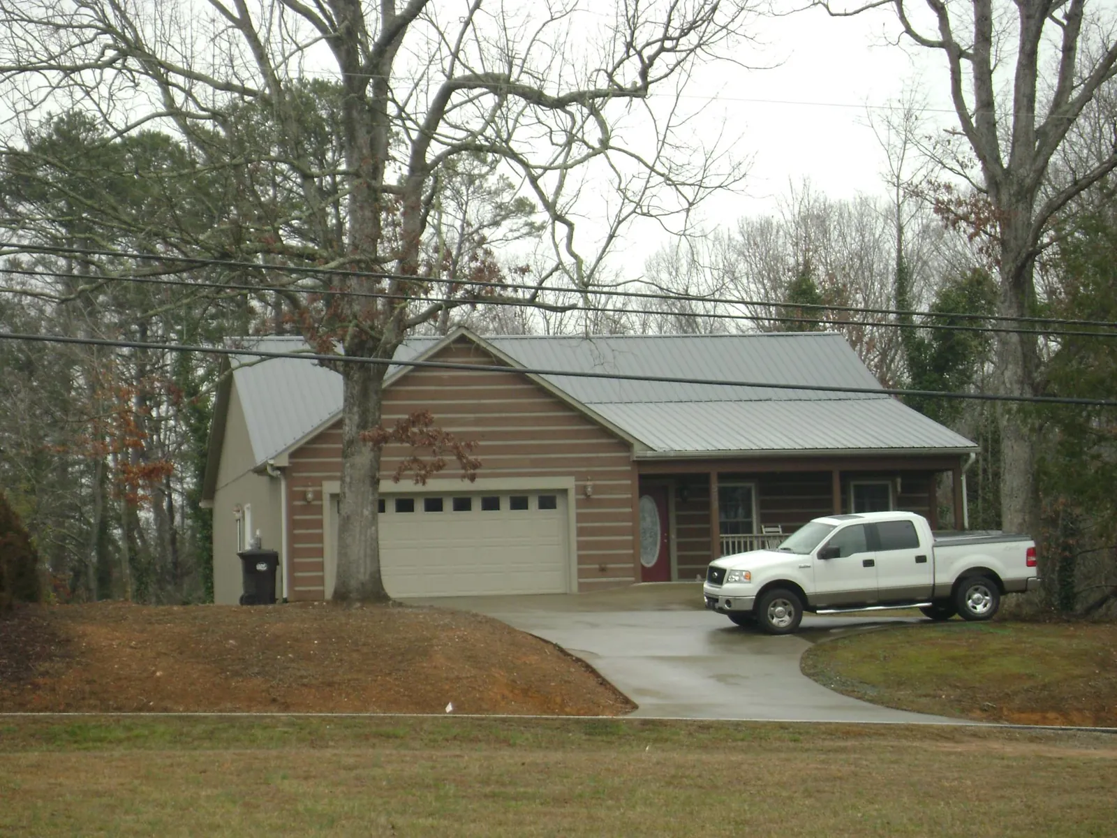Gray metal roof on a log sided house with an attached two car garage in Rochester Mills