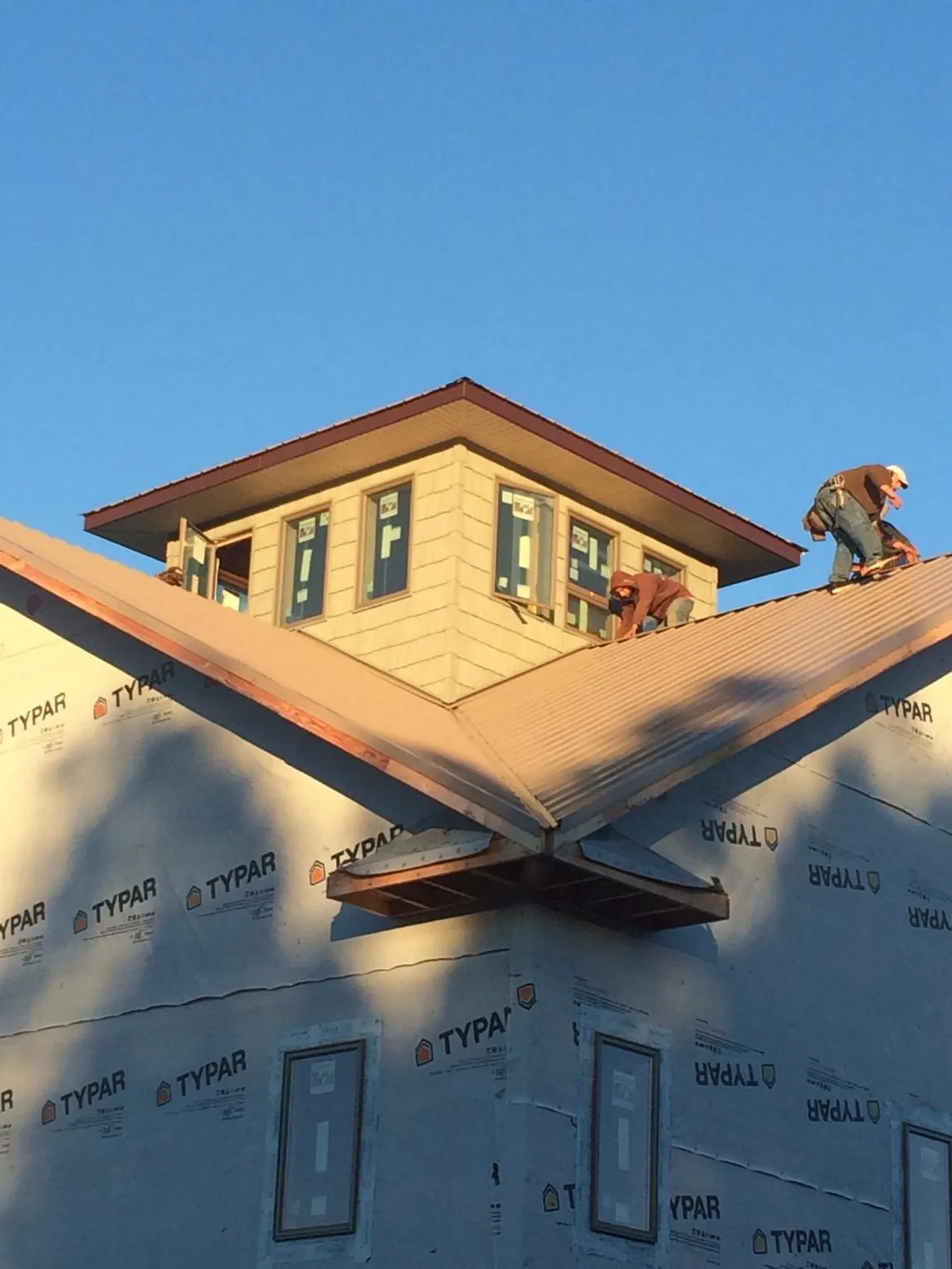 Roofers working around a rooftop cupola on a new metal roof at sunset — Roof Waterproofing in Rochester Mills by Roofing Brothers